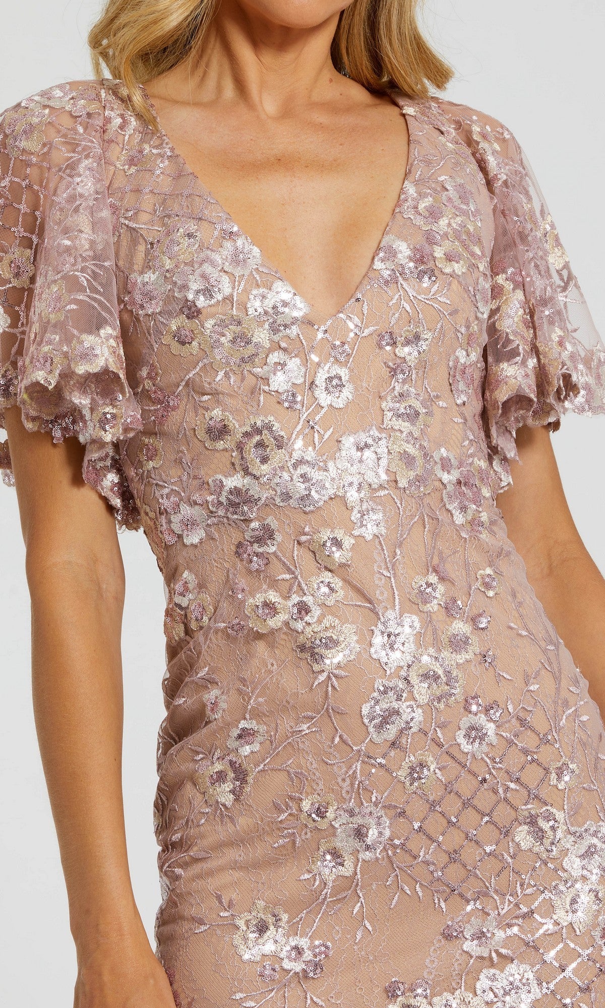 Woman wearing the Mac Duggal 68743 Long Formal Dress in light mauve, featuring floral embroidery, short flutter sleeves, and a deep V-neckline.
